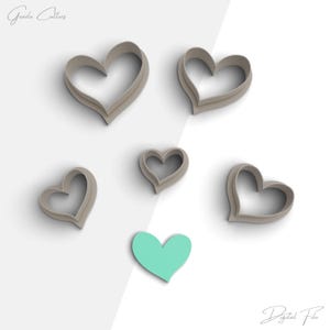 Può includere: Sei tagliabiscotti a forma di cuore di diverse dimensioni, con un solo tagliabiscotti a forma di cuore turchese al centro.