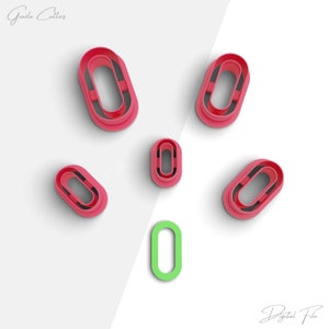 May include: Six red plastic cookie cutters shaped like an oval with a smaller oval inside. One green plastic cookie cutter shaped like an oval with a smaller oval inside.