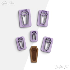 Puede incluir: Conjunto de seis cortadores de galletas de plástico morado en forma de ataúdes con una cruz en la parte superior. Un cortador de galletas de plástico marrón en forma de ataúd con una cruz en la parte superior. Archivo digital.