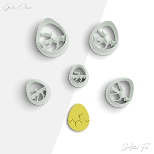 May include: Set of six cookie cutters in the shape of an egg with different designs. The cutters are white and made of plastic. The cutters are arranged on a white background. There is also a small yellow egg cookie cutter in the center of the image.