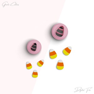 Puede incluir: Dos cortadores de galletas de plástico rosa con forma de maíz dulce, con cinco formas de maíz dulce naranja, amarillo y blanco sobre un fondo blanco. El texto "Archivo digital" está en la parte inferior de la imagen.
