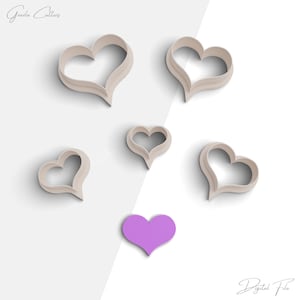 May include: Six heart-shaped cookie cutters in a light beige color, with one purple heart-shaped cookie cutter in the center. The cookie cutters are arranged in a scattered pattern on a white background. The text "Digital File" is visible in the bottom right corner.