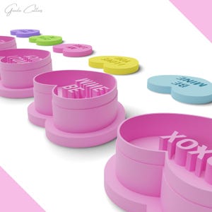 Puede incluir: Conjunto de cortadores de galletas en forma de coraz&oacute;n rosa con diferentes mensajes del D&iacute;a de San Valent&iacute;n, que incluyen "Be Mine", "XOXO" y "You Are My Love".