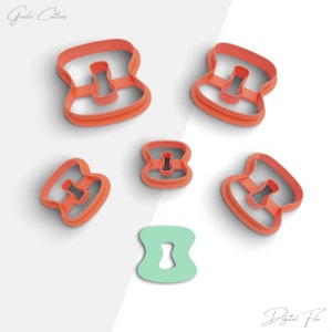 May include: Several orange plastic keyhole-shaped cookie cutters, each with a keyhole cutout. One cutter is light green. The cutters are on a white surface. The image includes the text "Grazia Cutters" and "Digital File".