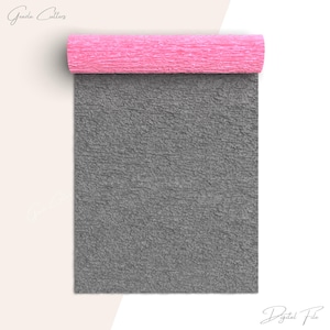 Puede incluir: Un rollo de papel crepé gris con un rollo de papel crepé rosa en la parte superior. El papel crepé gris es texturizado y el papel crepé rosa es liso.