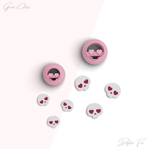 Puede incluir: Cortadores de galletas de calavera rosa con ojos en forma de corazón. También hay seis cortadores de galletas de calavera blanca más pequeños con ojos en forma de corazón rosa.