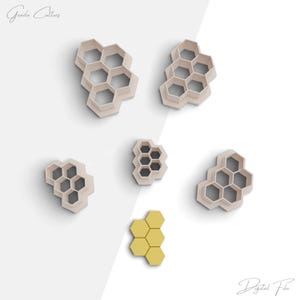 May include: Set of six cookie cutters shaped like honeycombs. The cutters are made of white plastic and are arranged on a white background. The cutters are different sizes and are arranged in a staggered pattern.