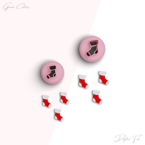 Puede incluir: Cortadores de galletas con forma de calcetín navideño. La imagen muestra dos cortadores circulares rosas con un diseño de calcetín, y seis pequeñas formas de calcetín rojas y blancas. El texto "Geazla Cutters" y "Digital File" son visibles.