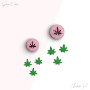 Może przedstawiać: Dwa różowe wykrawacze do ciasteczek w kształcie liści marihuany i pięć zielonych wykrawaczy do ciasteczek w kształcie liści marihuany na białym tle. Tekst "Plik cyfrowy" znajduje się na dole obrazu.