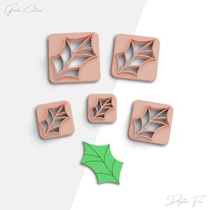 Op de afbeelding: Set van vijf koekjesvormen in de vorm van een hulstblad. De vormen zijn gemaakt van lichtroze plastic en zijn gerangschikt op een witte achtergrond. Een enkel groen hulstblad is ook te zien op de afbeelding.