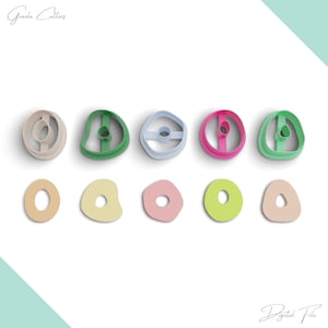 May include: Set of 10 cookie cutters in various shapes and colors. The cutters are arranged in two rows. The top row features five cutters in different colors: beige, green, light blue, pink, and green. The bottom row features five cutters in different colors: beige, light yellow, pink, light green, and beige. The cutters are all in the shape of a donut.