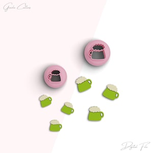 Peut inclure: Un ensemble d'emporte-pièces en plastique rose et vert en forme de chopes de bière. Les emporte-pièces sont disposés sur une surface blanche. Le texte "Fichier numérique" est visible dans le coin inférieur droit de l'image.