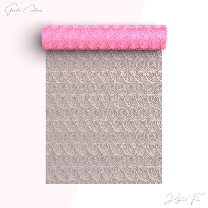 Puede incluir: Un rodillo de silicona rosa y gris con un patrón repetitivo de círculos superpuestos. El rodillo está enrollado y el patrón es visible en ambos lados, rosa y gris.