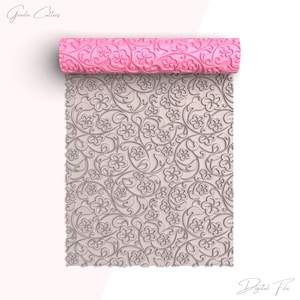 Puede incluir: Un rodillo rosa con un patrón floral y un diseño en relieve a juego. El rodillo está desenrollado, revelando un detallado patrón floral. El texto "Graza Cutters" y "Digital File" está presente.