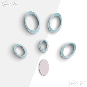 May include: Set of six light blue oval cookie cutters with a single light pink circle cookie cutter.  The cookie cutters are arranged in a scattered pattern on a white background.