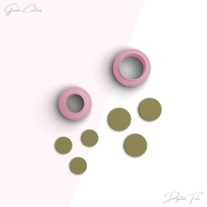 Peut inclure: Un ensemble de cinq emporte-pièces ronds. Deux sont roses et trois sont verts. Les emporte-pièces roses sont plus grands que les emporte-pièces verts. Les emporte-pièces sont disposés sur une surface blanche.