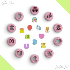 Op de afbeelding: Een set van 17 roze plastic koekjesuitstekers in verschillende vormen, waaronder een regenboog, een eenhoorn, een hart, een hoefijzer, een pot met goud, een klavertjevier, een jurk, een ballon en een paar andere vormen. De uitstekers zijn gerangschikt op een witte achtergrond.