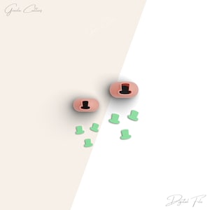 May include: Two pink silicone moulds with a top hat design. The moulds are surrounded by six green silicone moulds shaped like top hats.
