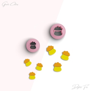 Może przedstawiać: Zestaw różowych plastikowych foremek do ciasteczek w kształcie worka z ziarnem i małej kupki ziaren. Formy znajdują się na białym tle. Plik cyfrowy.