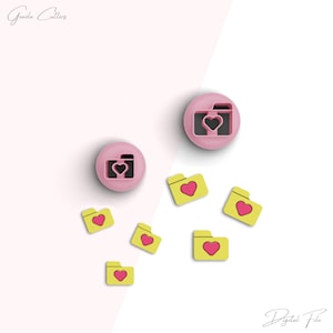 May include: A set of pink and yellow cookie cutters in the shape of a camera and folders with hearts. The camera cutter has a heart in the lens. The folder cutters have hearts in the center. The cutters are on a white background. Digital File.