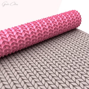 Puede incluir: Un rodillo rosa con una superficie texturizada, que se desenrolla para revelar un patr&oacute;n de hojas superpuestas. El rodillo est&aacute; dise&ntilde;ado para crear patrones decorativos en fondant o masa.