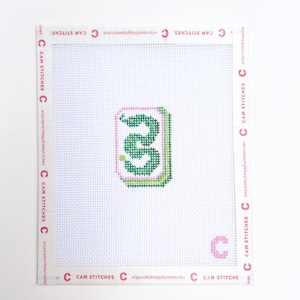 May include: Cross-stitch canvas featuring a green and pink number 3 design. The design is surrounded by a pink border. The canvas has the text "CAM STITCHES" and the Etsy shop URL printed around the edges.