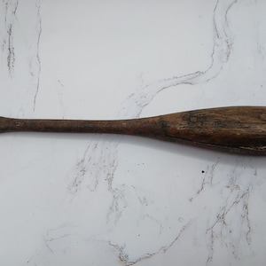 May include: A vintage wooden screwdriver with a brown wooden handle and a metal shaft. The handle has two metal screws.