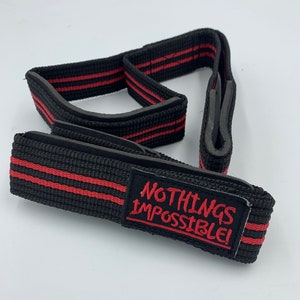 May include: Black lifting straps with red stripes and a red patch that says "NOTHING'S IMPOSSIBLE!"
