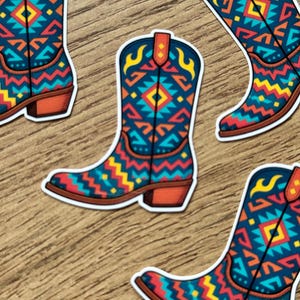 May include: Stickers of cowboy boots with a Southwestern design. The boots are navy blue with red, yellow, and turquoise geometric patterns. The heels and pull straps are orange.