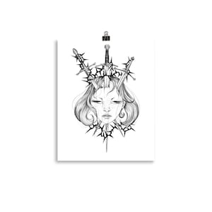 May include: Black and white art print featuring a detailed illustration of a woman's face with closed eyes, adorned with swords and thorny elements. The artwork is held in place by a binder clip.