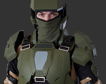 May include: Olive green tactical armor set, including a helmet, chest plate, and shoulder guards. The helmet has a visor and ear protection. The chest plate features a rectangular design with metallic accents. The person is wearing a balaclava.