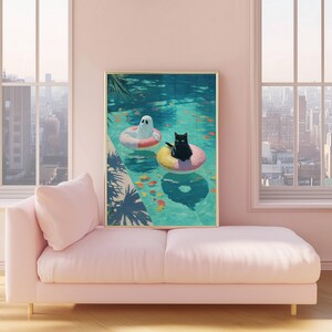 Op de afbeelding: Een ingelijste kunstdruk toont een grillige zwembadsc&egrave;ne. Een zwarte kat en een spook drijven in het water op opblaasbare ringen. Het zwembad is omgeven door tropische planten. Het kunstwerk wordt tentoongesteld op een roze bank.