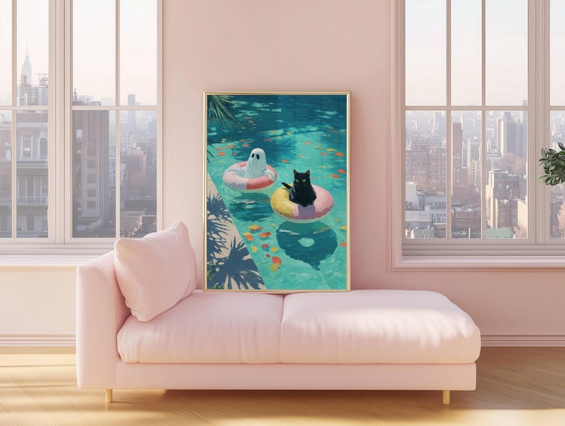 Op de afbeelding: Een ingelijste kunstdruk toont een grillige zwembadsc&egrave;ne. Een zwarte kat en een spook drijven in het water op opblaasbare ringen. Het zwembad is omgeven door tropische planten. Het kunstwerk wordt tentoongesteld op een roze bank.