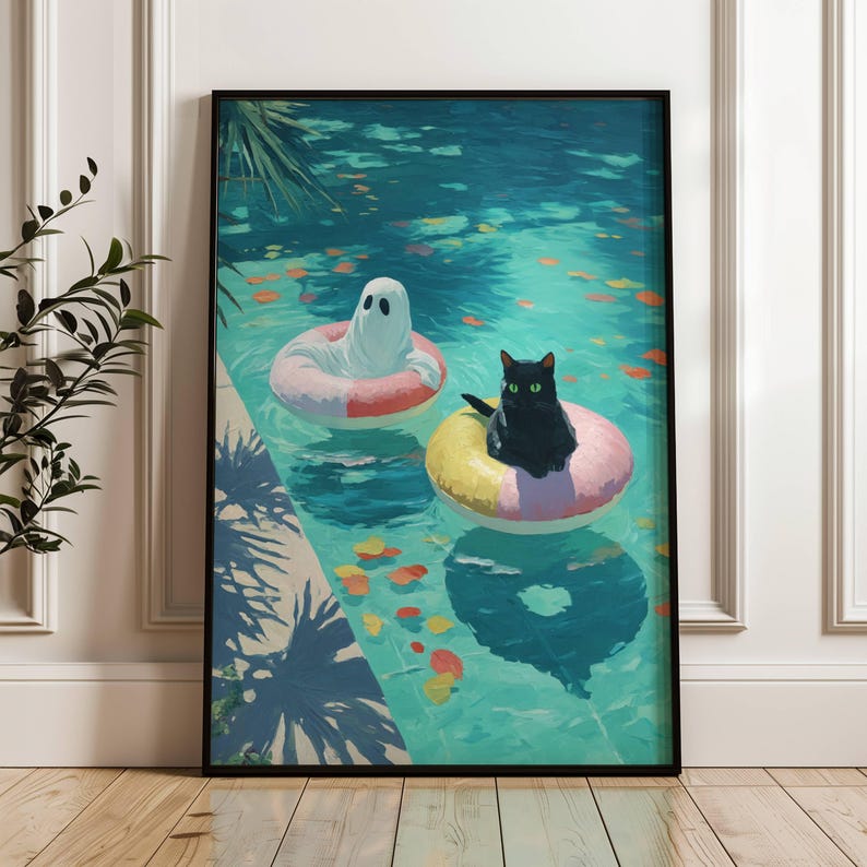Op de afbeelding: Ingelijste kunstafdruk met een grillige sc&egrave;ne van een zwarte kat en een spook die in een zwembad op opblaasbare ringen drijven. Het zwembadwater is turquoise, met kleurrijke bladeren. Het kunstwerk is in een zwarte lijst.