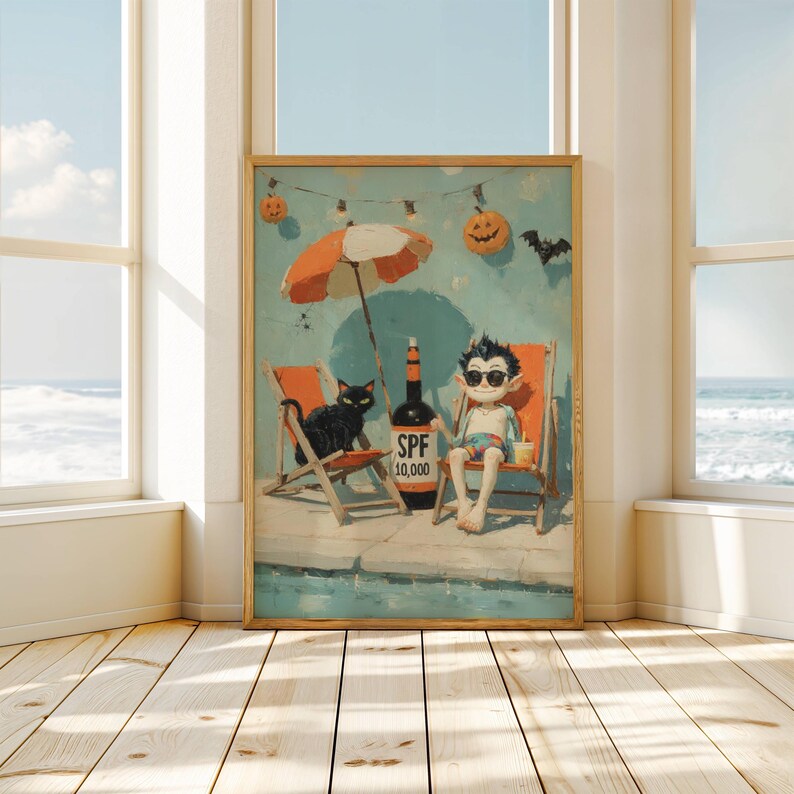 May include: A framed print depicts a whimsical beach scene with a vampire character, a black cat, and a bottle of SPF 10,000. The artwork features an orange and white umbrella, beach chairs, and Halloween decorations. The background shows a blue sky and ocean.