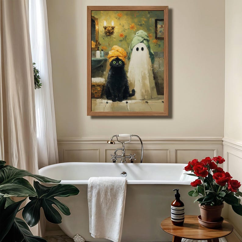 May include: A framed artwork depicts a black cat and a ghost in a bathroom setting. The cat wears a yellow towel on its head, while the ghost is draped in a white sheet and a green towel. The background features floral wallpaper and bathroom fixtures.