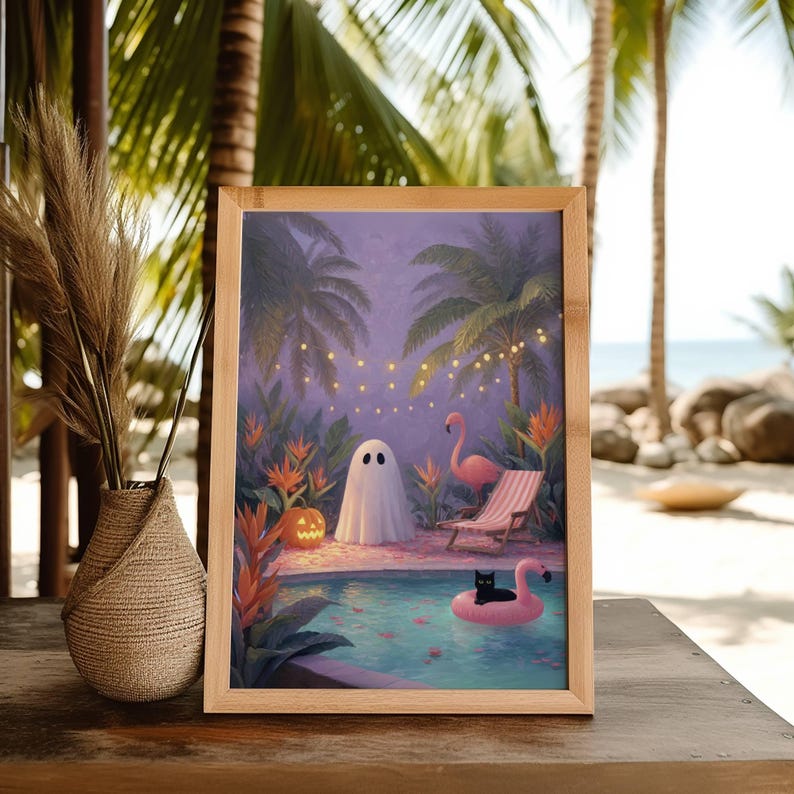 May include: A framed print depicts a whimsical Halloween scene at a tropical pool. A white ghost stands near a jack-o'-lantern, a pink flamingo float, and a black cat. Palm trees and string lights create a festive atmosphere. The frame is made of light-colored wood.