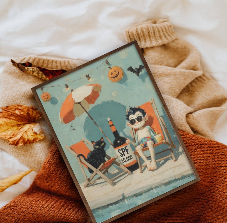 May include: A framed art print depicts a vampire relaxing on a beach chair with a black cat, under an orange and white umbrella. A bottle of SPF 10,000 sunscreen sits nearby. The scene is set against a blue sky with Halloween decorations.