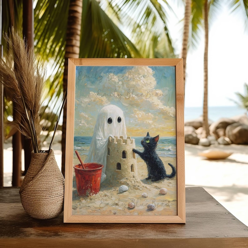Puede incluir: Una impresi&oacute;n art&iacute;stica enmarcada representa una escena de playa caprichosa. Una figura de fantasma y un gato negro construyen un castillo de arena junto a un cubo rojo. La obra de arte est&aacute; ambientada en una playa arenosa con conchas marinas, bajo un cielo nublado. El marco es de madera clara.