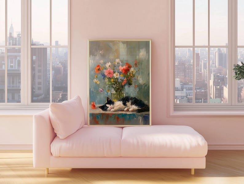 May include: A framed painting depicts a black and white cat resting near a vase of colorful flowers. The artwork is displayed on a teal surface, set against a soft, blurred background. The painting is in a gold frame, and the scene is set in a room with a pink sofa.