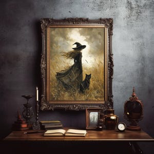 May include: A framed artwork depicts a witch in a black dress and hat, standing in a field with a black cat. The artwork is in a dark, ornate frame, displayed on a wooden table with other decorative items, including a candle and books.