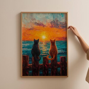 May include: Two cats, one black and one orange, sit on a wooden fence overlooking a blue ocean with a sunset in the background.
