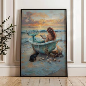 May include: A framed wall art print depicting a mermaid with long red hair sitting in a light blue clawfoot bathtub on a sandy beach at sunset. A black cat sits nearby, and a stack of books with lit candles rests beside the tub near the ocean waves.