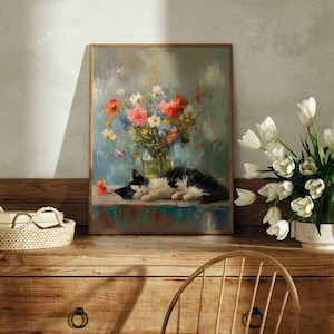 May include: A framed painting of a black and white cat sleeping next to a vase of colorful flowers. A bouquet of white tulips sits in a white vase on a wooden dresser. A woven basket with glasses rests on the dresser.
