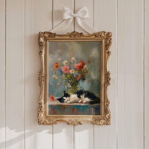 May include: Ornate gold framed painting of a black and white cat resting on a table, with a vase of colorful flowers. The painting is hung with a white ribbon and bow. The artwork has a vintage aesthetic.