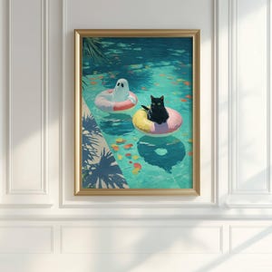 Op de afbeelding: Ingelijste kunstdruk met een zwarte kat en een geest die in een zwembad op opblaasbare ringen drijven. Het zwembadwater is turquoise, met kleurrijke vissen en reflecties. Het kunstwerk is ingelijst in een goudkleurige lijst.