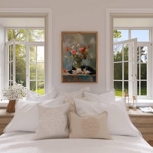 May include: A bedroom scene featuring a bed with white bedding and decorative pillows. A framed painting of a cat and flowers hangs above the bed. Two windows with open panes offer a view of a lush green landscape.