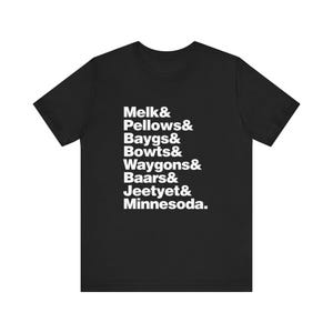 Puede incluir: Una camiseta negra de manga corta con texto blanco impreso en la parte delantera. El texto dice: Melk& Pellows& Baygs& Bowts& Waygons& Baars& Jeetyet& Minnesoda. La camiseta tiene un cuello redondo y un corte estándar con mangas cortas.