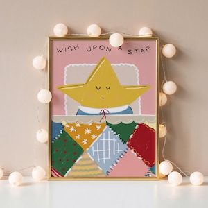May include: A framed print with a cartoon star sleeping under a patchwork quilt. The text "WISH UPON A STAR" is at the top. The artwork is in a gold frame, with fairy lights around it. The quilt has various colours.