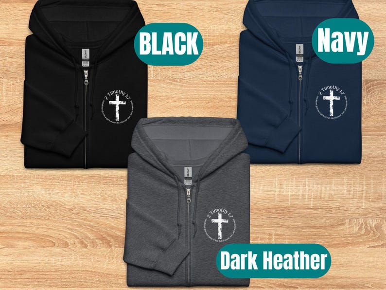 Puede incluir: Tres sudaderas con capucha y cremallera en negro, azul marino y gris oscuro jaspeado con una cruz blanca y el texto "2 Timoteo 1:7" impreso en la parte delantera.